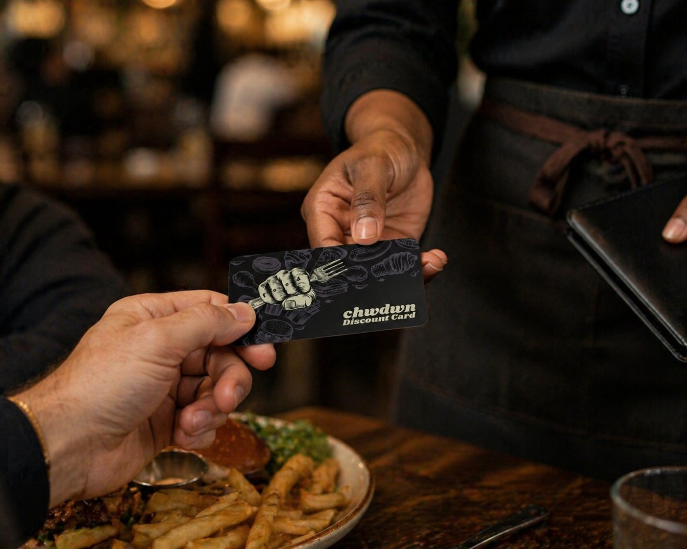 A server hands a chwdwn Discount Card across a restaurant table
